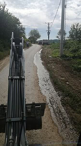 Radnička mašina na asfaltiranom putu u ruralnom okruženju.